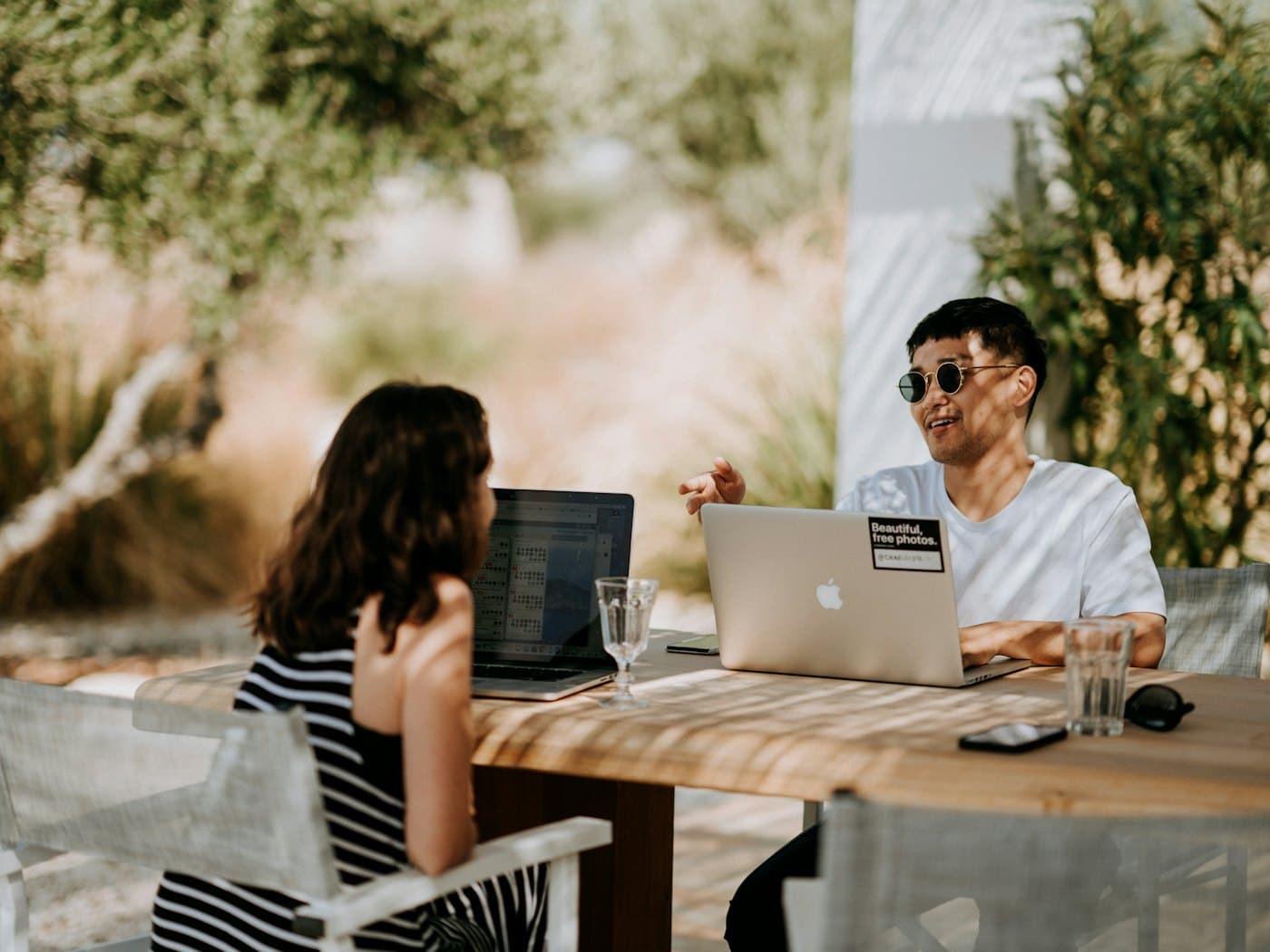 Two colleagues working from a laptop at an outdoor table
