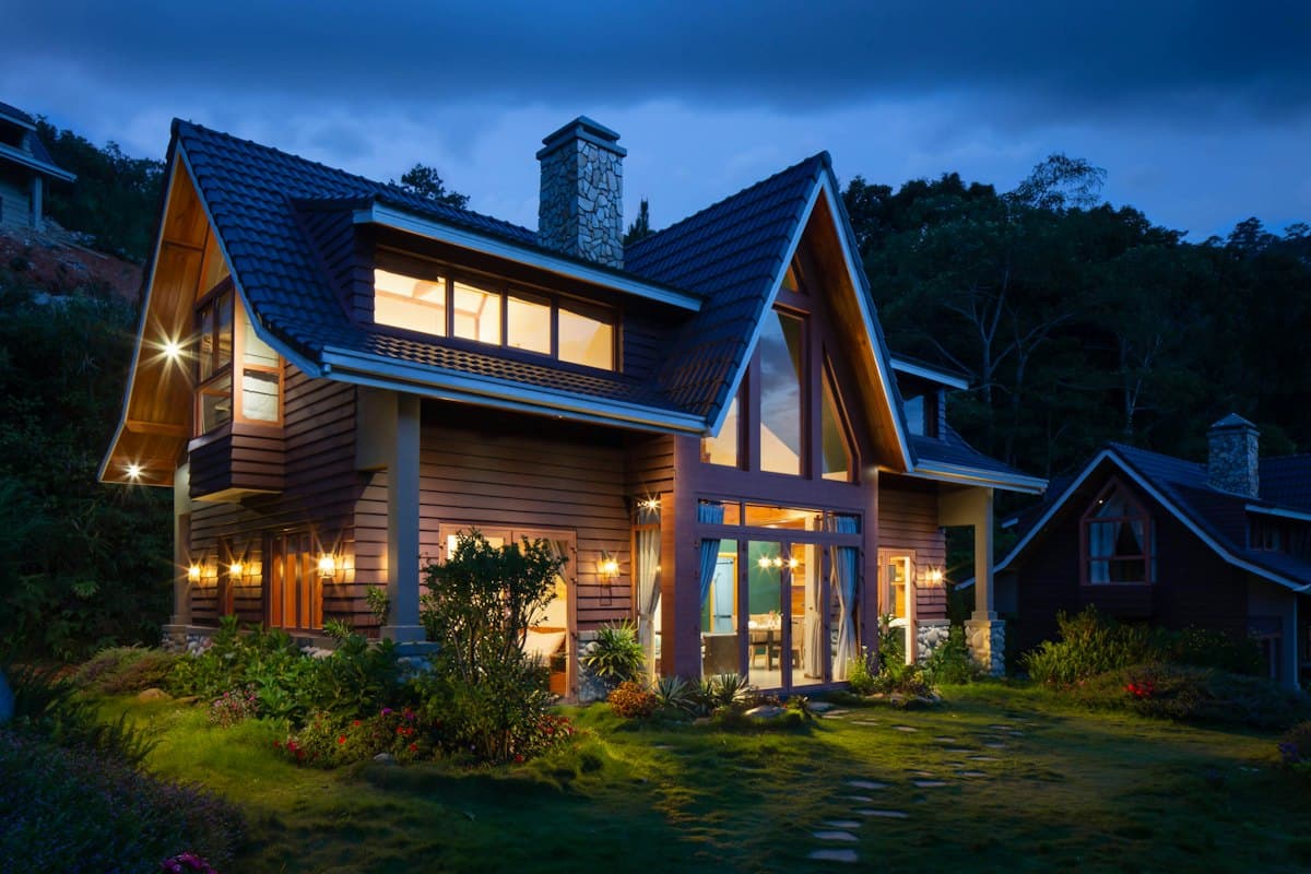 Gabled mountain cabin with warm interior light at twilight
